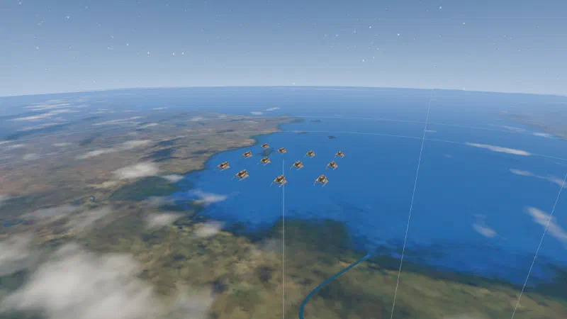 Twelve Striker fighters in three chevrons of four, flying high over a coastline and blue sea.