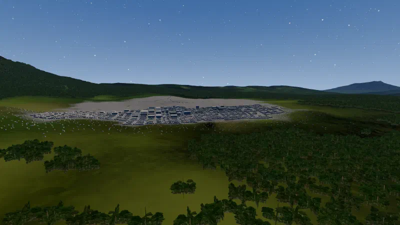 A generated town of low grey blocks on a green plain, forested ridges and a volcano behind.